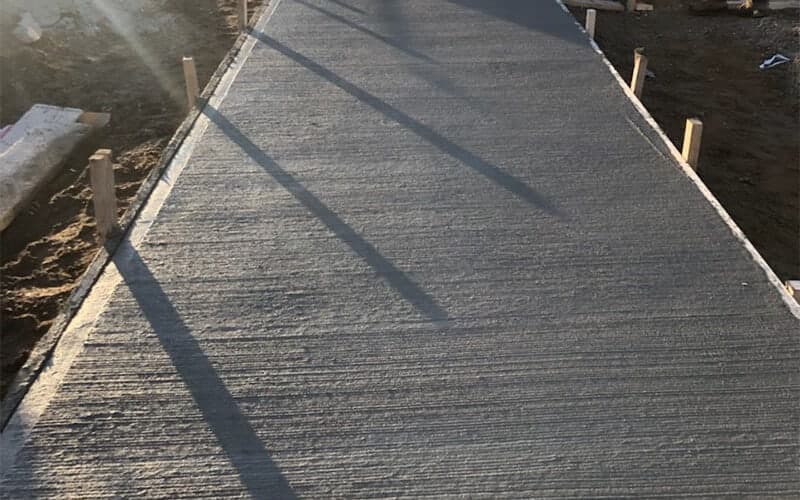 Broom-finished concrete walkway with clean edges freshly poured at a new construction site