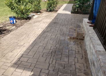 Stamped concrete patio with cobblestone pattern and brick border wall in a Tennessee backyard