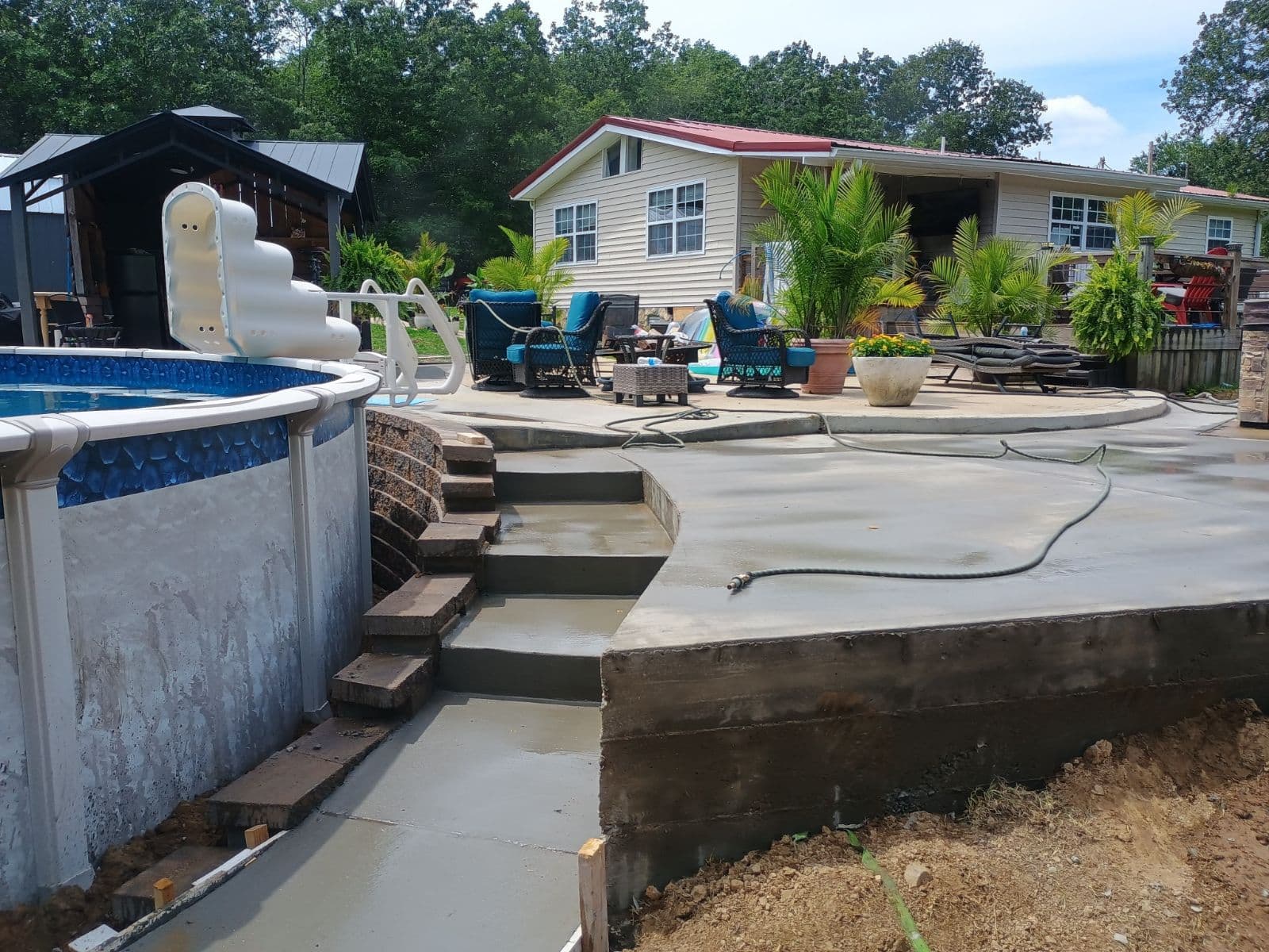 Custom concrete pool deck with steps and multi-level patio area built around an above-ground pool
